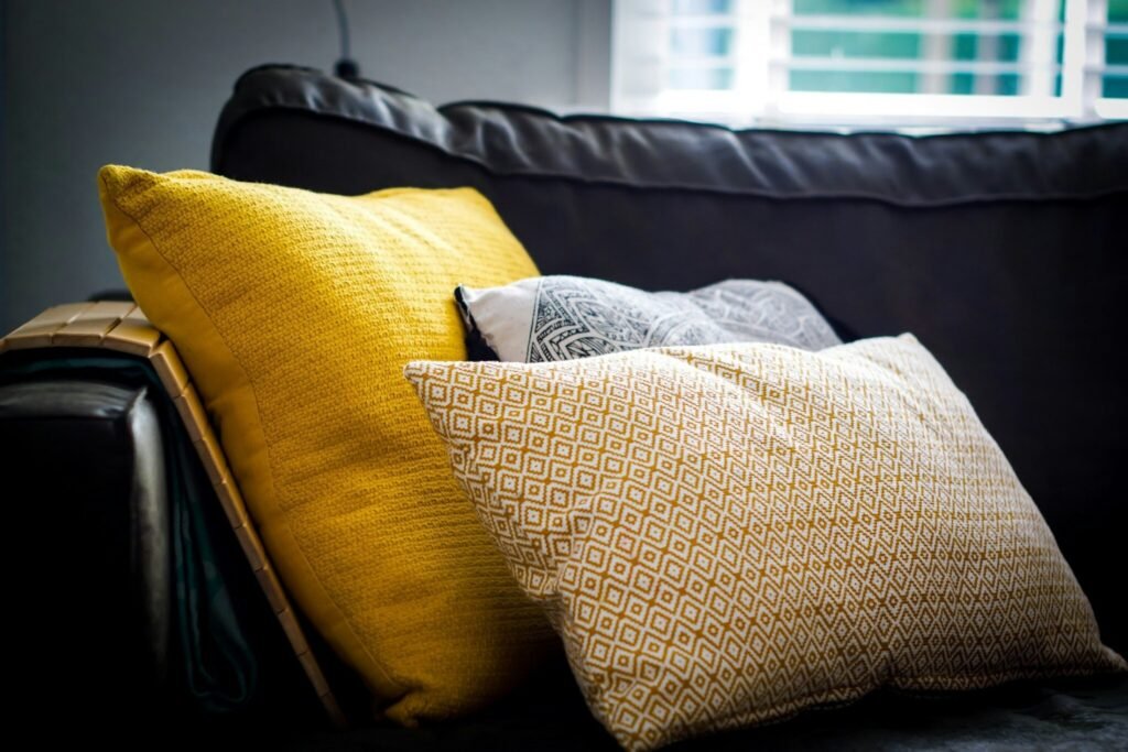 Three assorted-color throw pillows on black sofa
