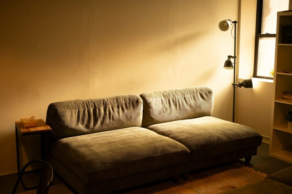 Sofa lit by a warm floor lamp in a dim living room